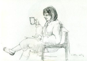 A woman sitting in a chair holding a cup.