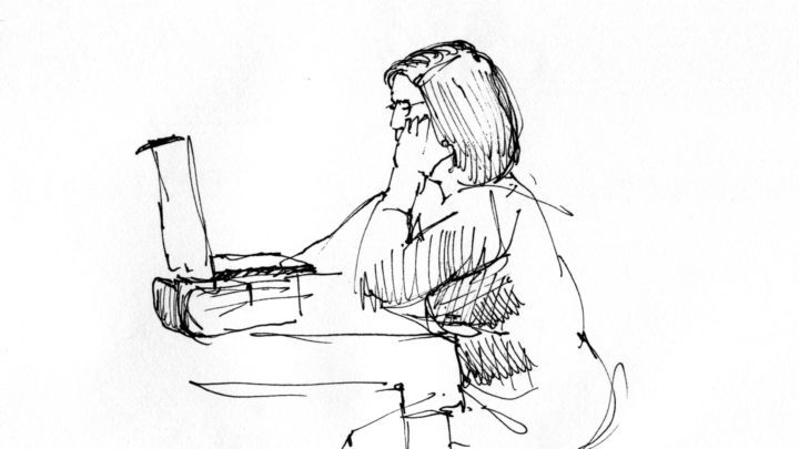 A woman sitting at a table with her laptop.